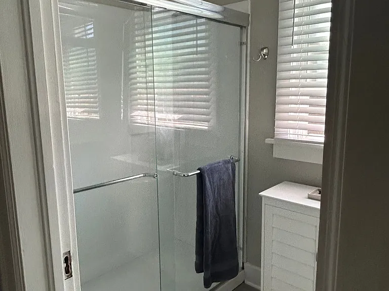 Brand new shower with glimpse of large window over floor cabinet.
