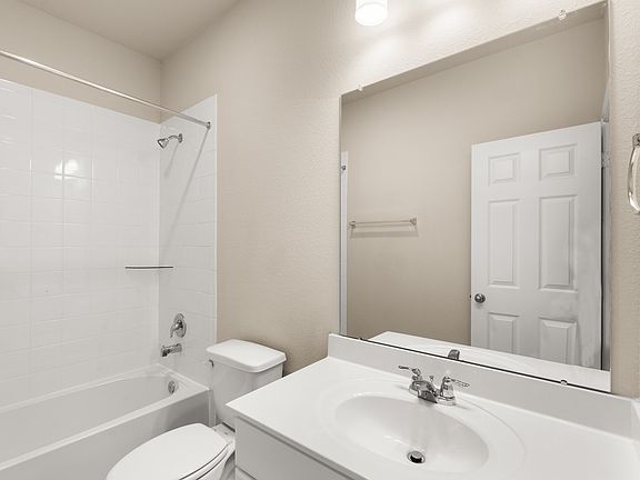 The secondary bath features tile flooring, white cabinetry with light countertops and a shower tub c