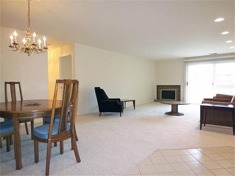 Huge bright living room with adjacent dining area features convenient gas fireplace & patio sliders 