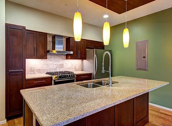 Modern kitchen well-equipped with stainless appliances; upgrades include pendant lighting over island, pull-out pantry, and upgraded range and dishwasher.  KitchenAid counter-depth fridge included!