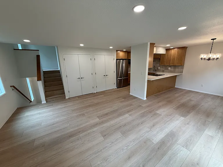 View from the fireplace showing the staircase up to the primary bedroom level and staircase down to front entry.