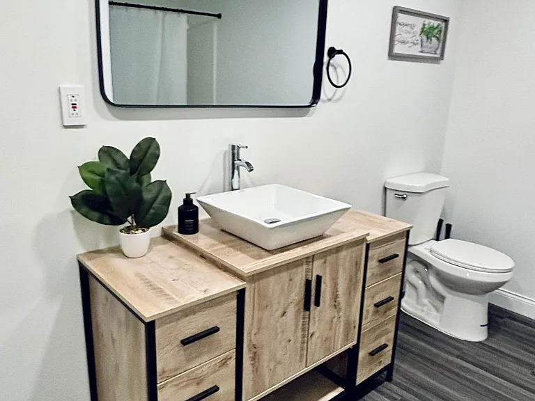 Full bathroom with wood vanity, vessel sink, large mirror, and a tub/shower combo for easy daily use.
