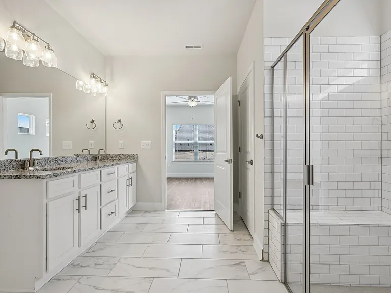 Luxurious primary bathroom featuring a double vanity, walk-in shower, and spacious walk-in closet.