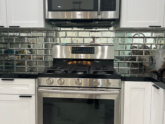 Kitchen with gas stove, built in micro wave and mirrored tile back splash.