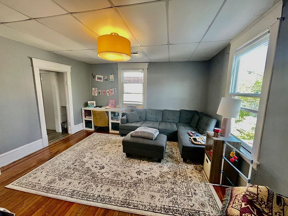 Spacious Living Room w/ Beautiful Original Hardwood Floors, Designer Paint, Designer Lighting, High Ceilings and Two Large Windows for Natural Lighting.