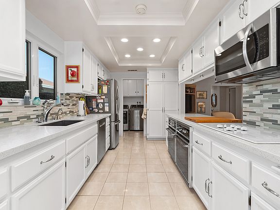 Kitchen with quartz counter tops, custom tile backsplash, stainless steel appliances including microwave, 2 ovens, dishwasher & refrigerator