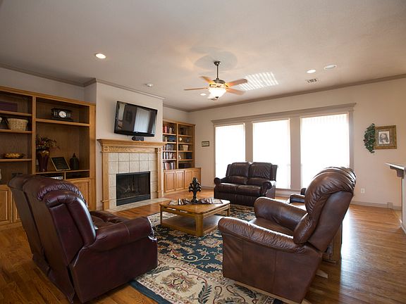 Open Family Room features hardwood floors, surround sound speakers, crown moulding, ceiling fan, recessed lighting, gas burning fireplace, three large windows overlooking back yard and built in cabinets and shelving.