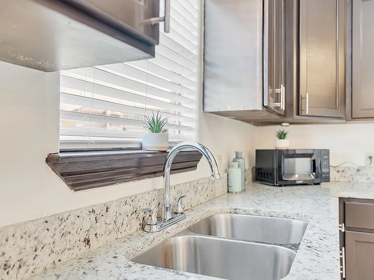 Stylish kitchen with granite countertops and a stainless steel sink located in Merida Vista Apartments, Laredo, Texas