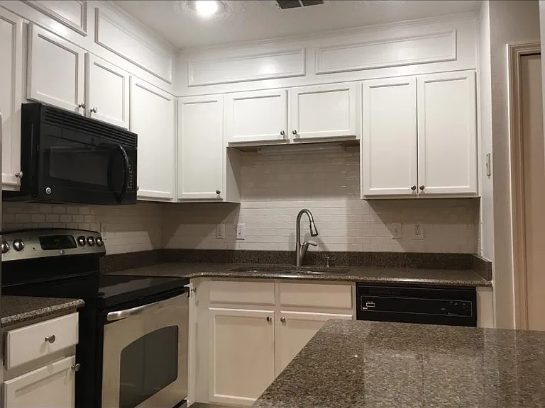 Stainless steel appliances. Granite countertops and white kitchen.
