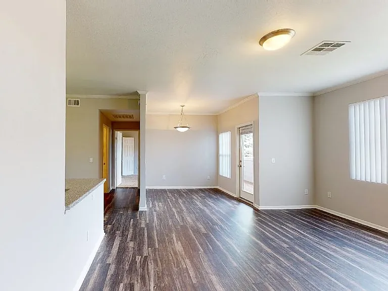 Apartment living room with wood-style flooring and patio or balcony in select homes.