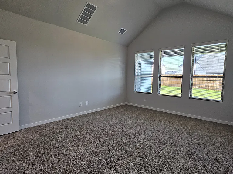 Relax in the spacious primary suite, featuring neutral tones and large windows overlooking the backyard