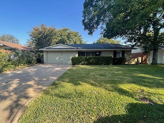 Ranch-style home featuring a garage and a front lawn