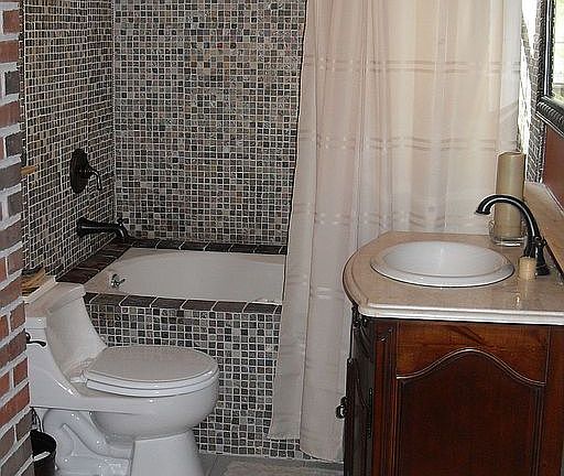 Custom tiling, furniture vanity, exposed brick wall in guest bathroom