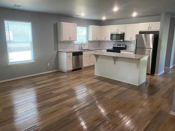 kitchen with island, open to living room. LTV flooring. Includes refrigerator