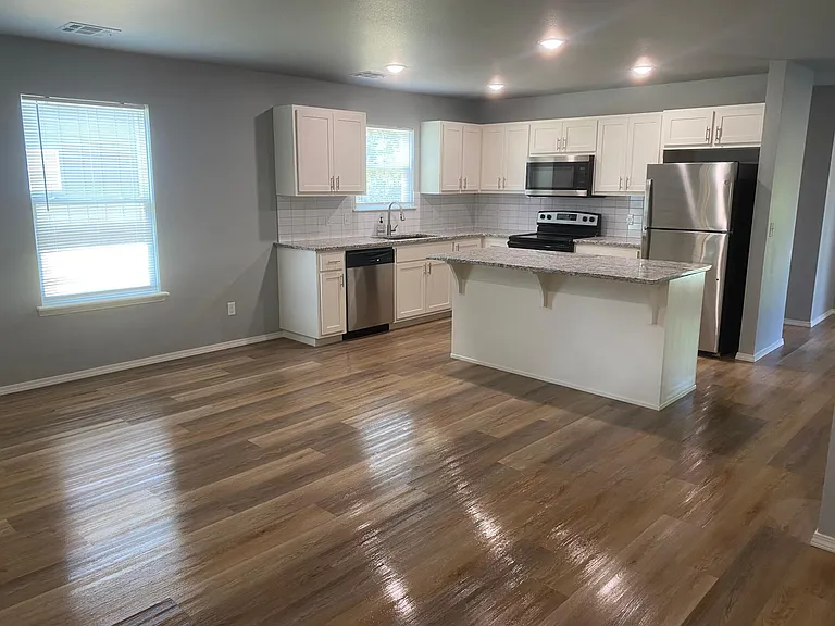 kitchen with island, open to living room. LTV flooring. Includes refrigerator