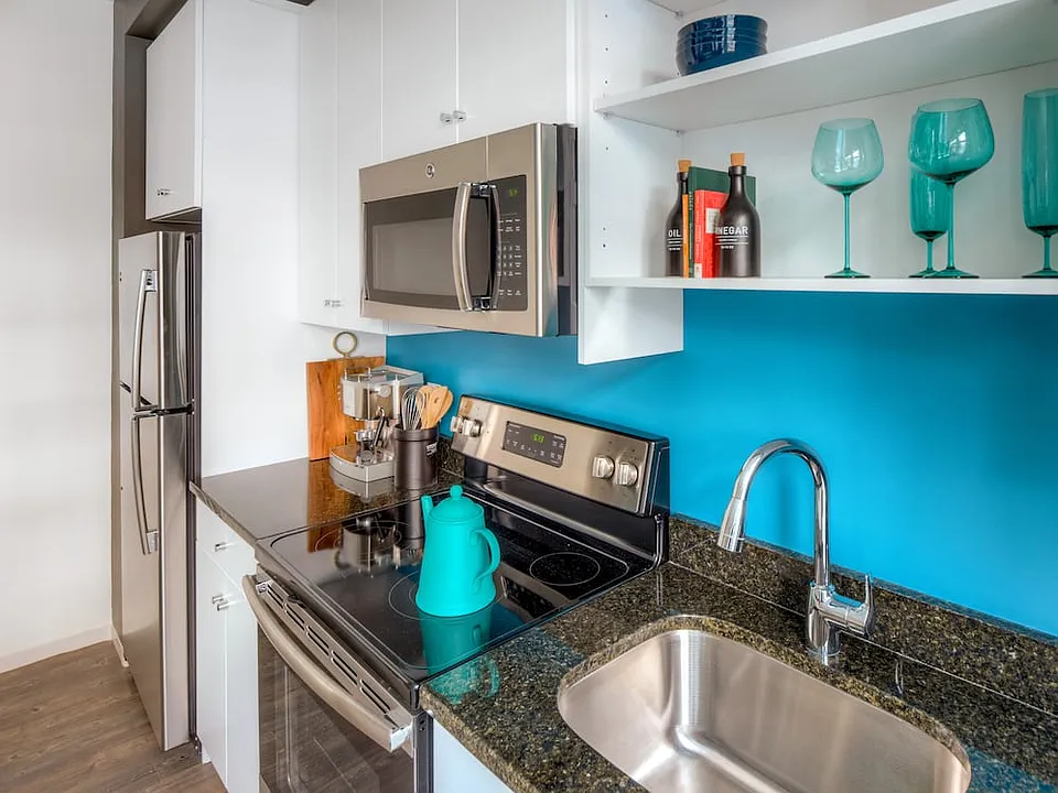 Kitchen with white cabinetry, granite countertops, stainless steel appliances and hard surface flooring