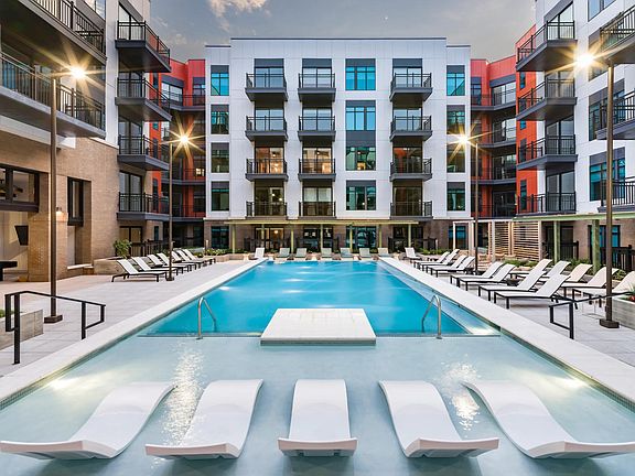 Resort-style pool courtyard with in-water loungers, sundeck seating, and private balconies surrounding the space.