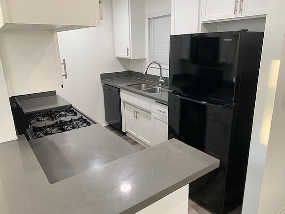 Modern kitchen with quartz countertops plus refrigerator, gas range, stove, microwave, dishwasher, and garbage disposal.