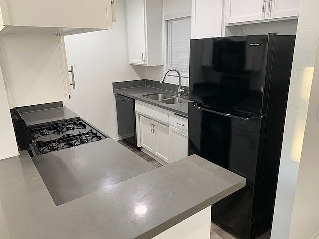 Modern kitchen with quartz countertops plus refrigerator, gas range, stove, microwave, dishwasher, and garbage disposal.