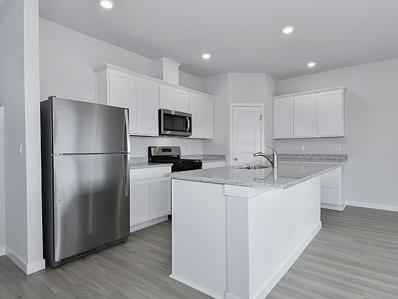 The kitchen has stainless steel appliances and plank flooring.