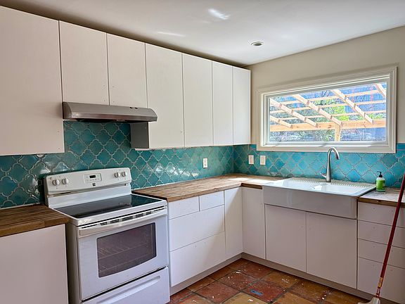 Kitchen w/ large bay window to back yard, Saltillo tiled floor and turquoise tiled back-drop!