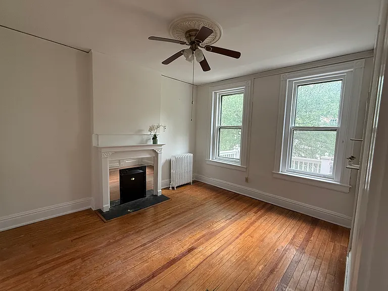 Bedroom 1 with decorative fireplace, ample natural light and ceiling fan.