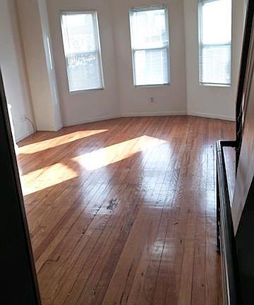 View into the living room. Bright light and original hardwood floors