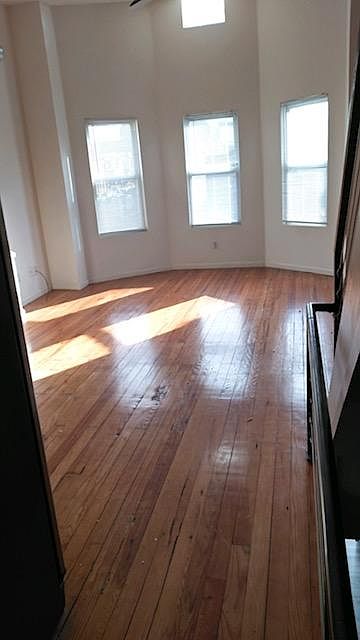 View into the living room. Bright light and original hardwood floors