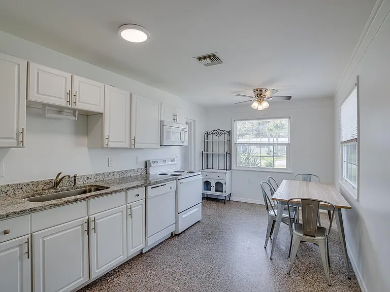 Large eat-in kitchen with granite counters, terrazzo floor, and ceiling fan. Access to 3/4 bath.