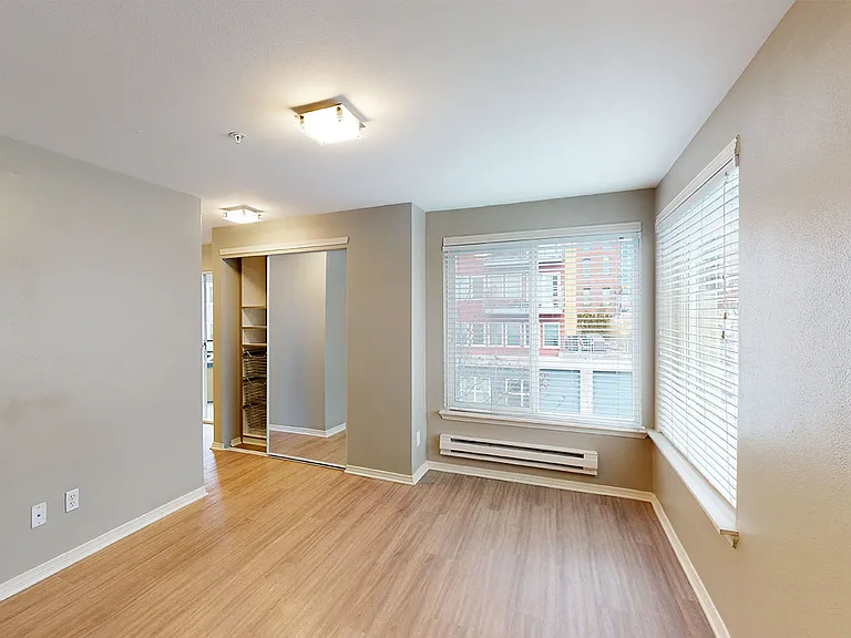 Spacious apartment bedroom with wood-style flooring.