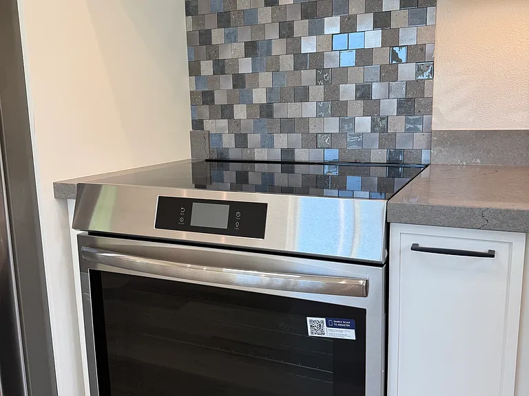 Induction slide in stove with stylish backsplash and professional grade hood.