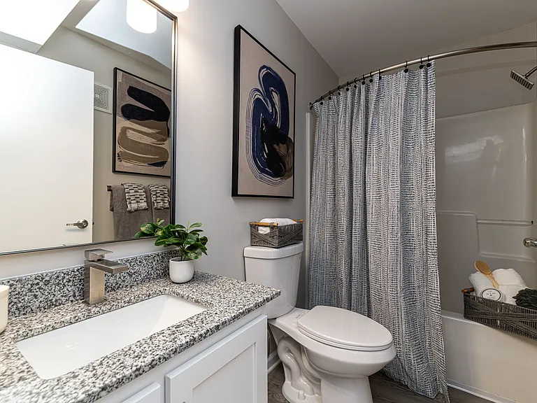 Bright bathroom with granite counters, high-rise faucet, and bathtub