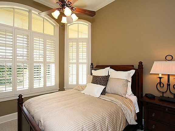 Guest bedroom with neutral paint, crown moulding and plantation shutters.