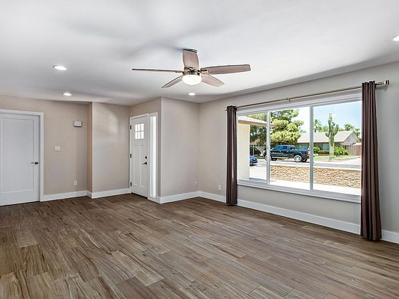 Front Living Room, Tile Wood flooring throughout with 5" baseboards, Taupe Colored walls, and grommet curtains.