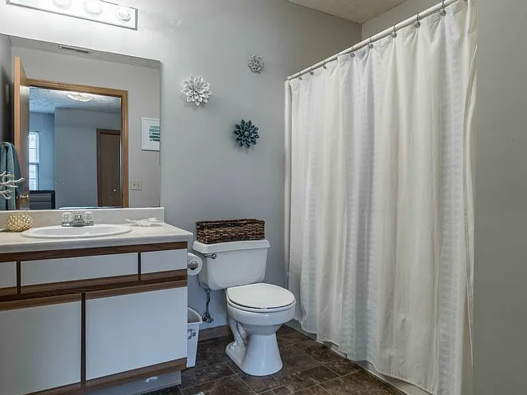 Start your day in a bright and spacious bathroom featuring a large mirror, full-size vanity, and tub-shower combo.