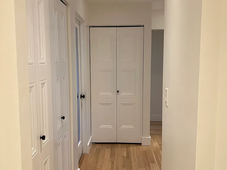 Hallway facing bottom of stairs (laundry on the left and one large bedroom - not primary- at the end of the hall)