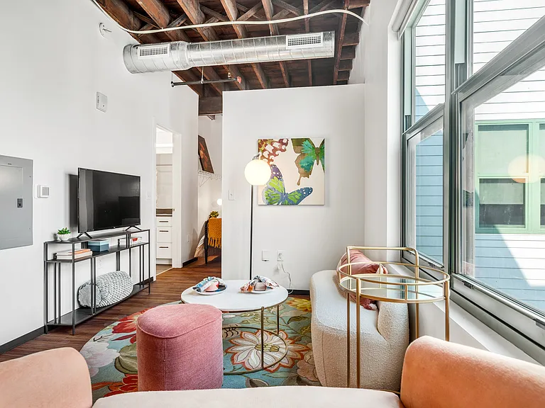 Bohemian Lounge: A cozy living area accentuated by artistic touches, plush seating, vibrant rugs, and ample natural light through expansive windows.
