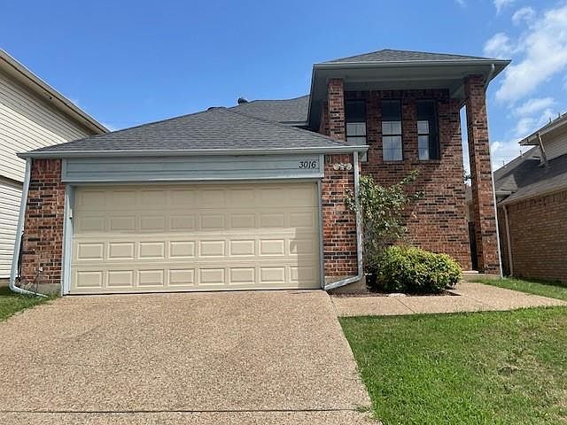 View of front facade featuring a front yard and a garage