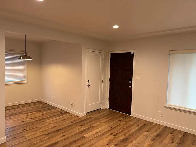 Central living space featuring a seamless layout with the living room to the right, dinning room to the left, front entry access, and convenient interior access to the two car garage.