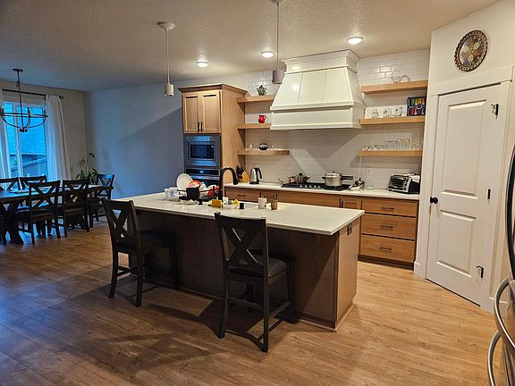 Modern Kitchen with island for quick snack seats and sink, extending to accommodate dining table with a large window.