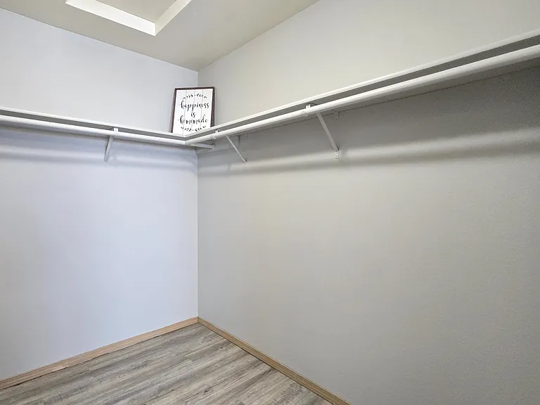Spacious master walk-in closet with wraparound shelving and hanging space, offering plenty of room to stay organized and maximize storage.