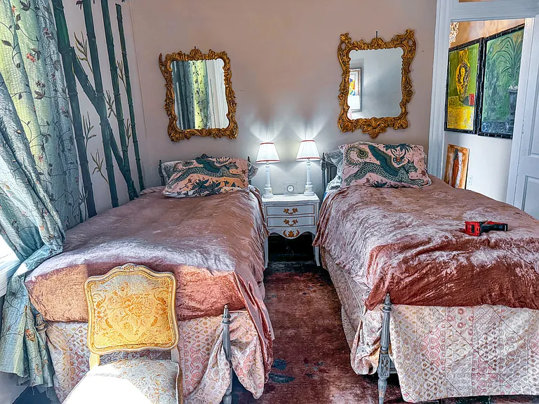 Bamboo mural with matching gilt framed mirrors over twin beds.