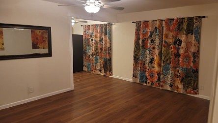Spacious Living Area with new flooring, paint, ceiling fans.