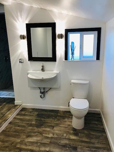 bathroom with TOTO toilet with soft closing lid, custom sink with chrome waterfall faucet and plumbing, designer light fixtures.