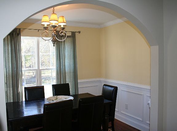 Dining room with wide arched entryway and wainscoating
