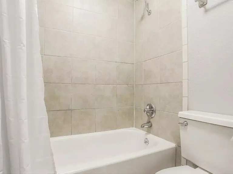 Bright, modern bathroom featuring elegant tiled walls and a pristine white bathtub with chrome fixtures.