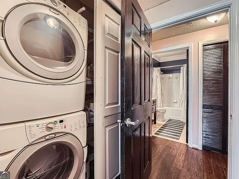 Convenient stacked washer and dryer hidden behind doors in mini-hallway to bedroom.