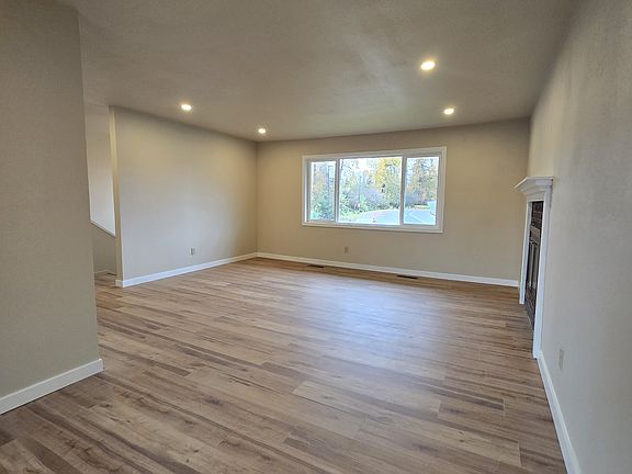 Open living room with picture window, fireplace. Updated lighting.