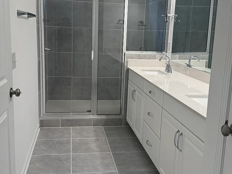 Luxurious primary bathroom with dual vanities and oversized walk-in shower.