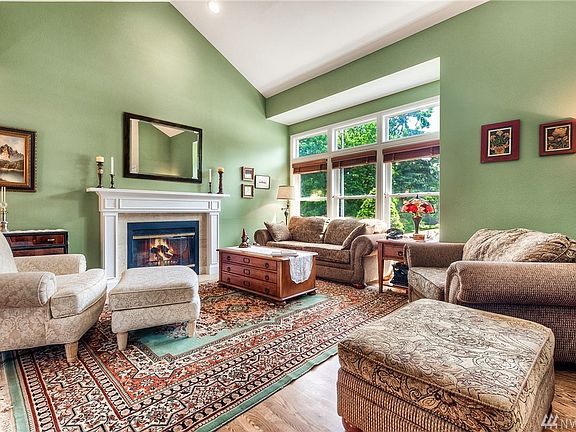 Soaring vaulted ceilings, wood burning fireplace with custom built mantle, hardwood floors and white vinyl windows.